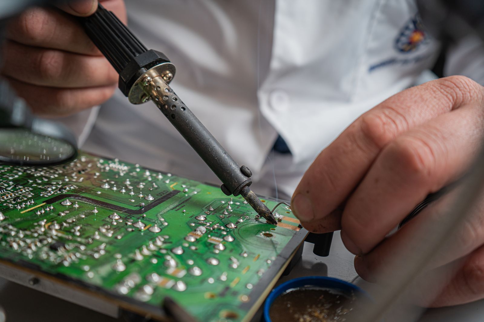 Hands soldering a circuit board during a repair
